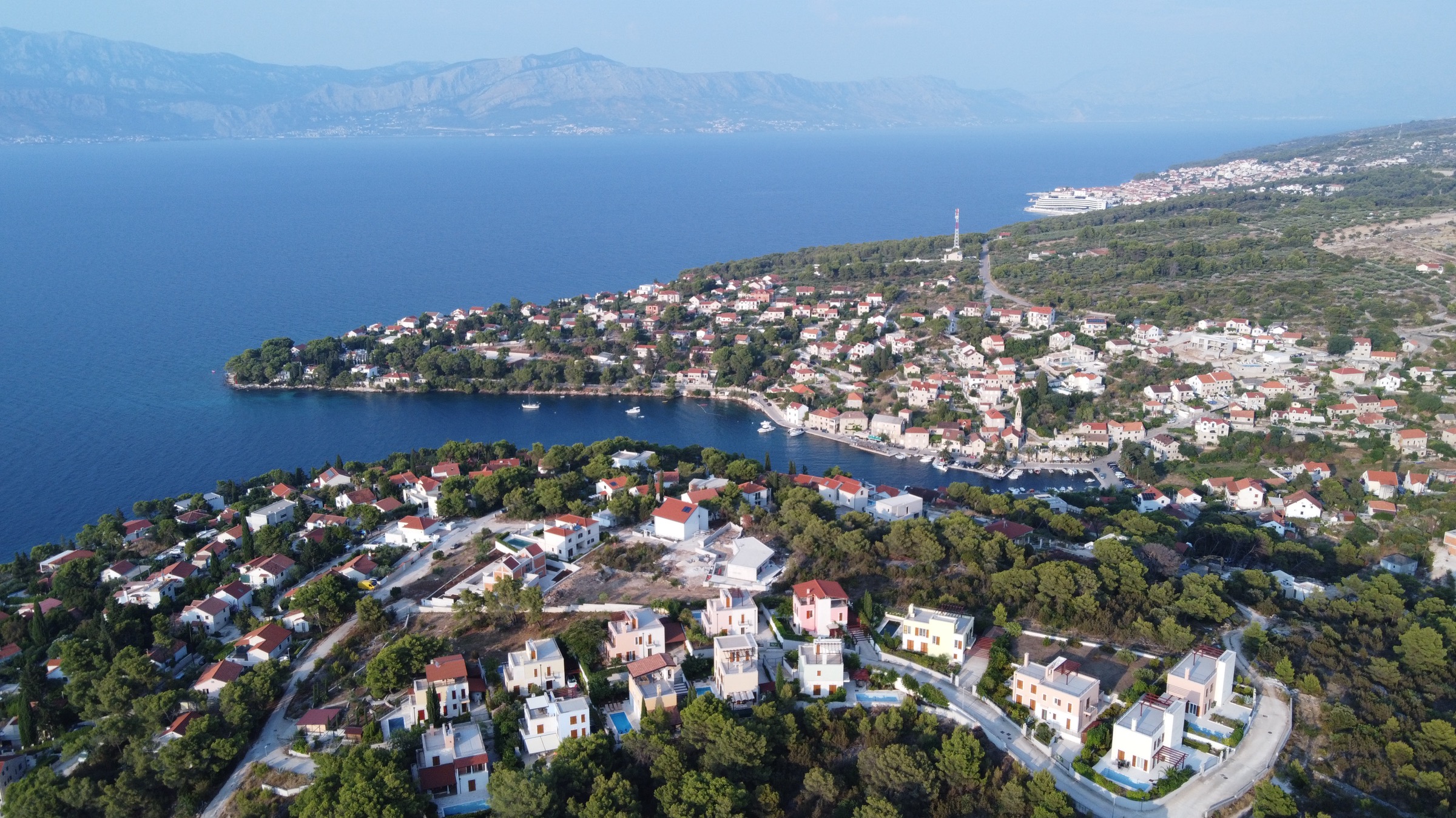 Aerial view of the villas above Splitska bay on Brač, with the sea and the mainland mountains behind